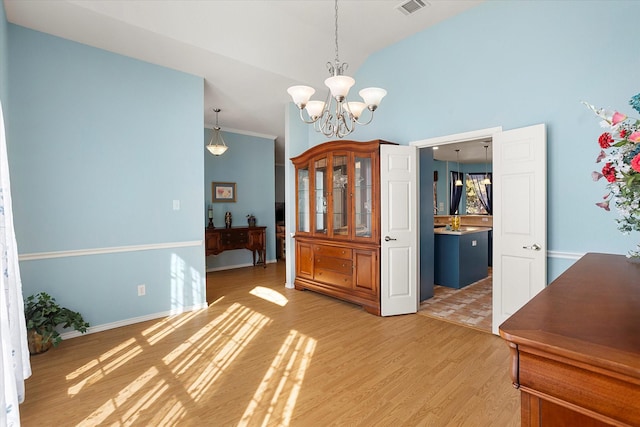 unfurnished dining area featuring hardwood / wood-style floors, lofted ceiling, and an inviting chandelier