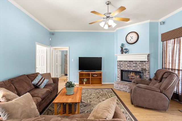 living room with a brick fireplace, light hardwood / wood-style floors, ceiling fan, and ornamental molding