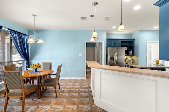 kitchen with hanging light fixtures, blue cabinets, sink, and stainless steel refrigerator with ice dispenser