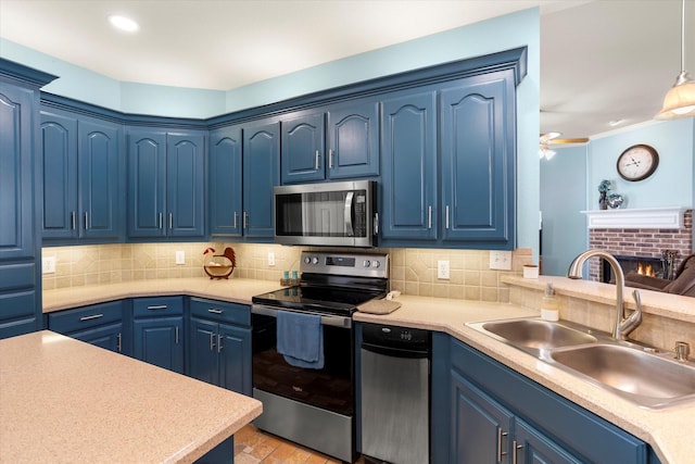 kitchen with blue cabinetry, hanging light fixtures, stainless steel appliances, sink, and tasteful backsplash