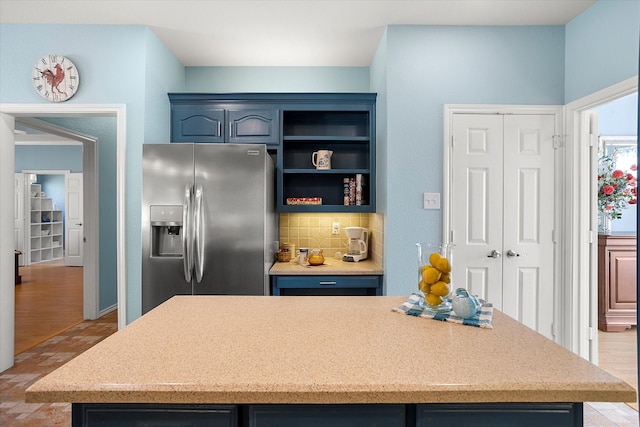 kitchen featuring blue cabinetry, stainless steel refrigerator with ice dispenser, and decorative backsplash