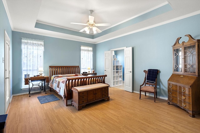 bedroom featuring ornamental molding, light hardwood / wood-style flooring, ceiling fan, and a raised ceiling