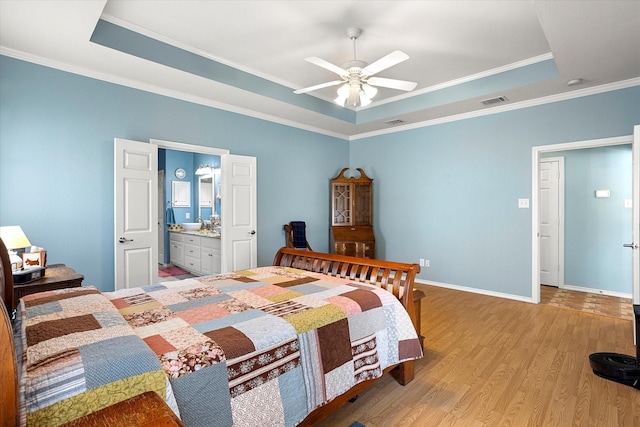 bedroom featuring a tray ceiling, ornamental molding, light wood-type flooring, and ceiling fan