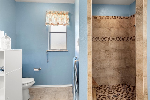 bathroom with a tile shower, tile patterned flooring, and toilet