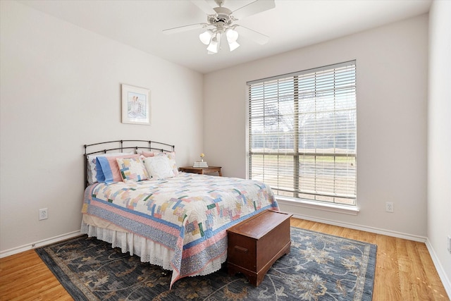 bedroom with ceiling fan, multiple windows, and hardwood / wood-style floors