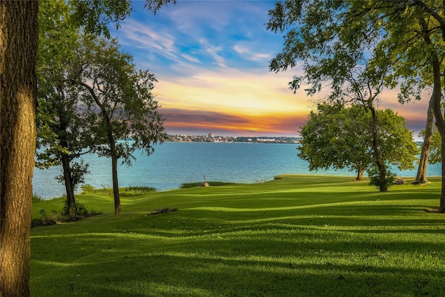 view of home's community with a water view and a lawn