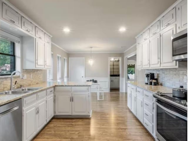 kitchen with stainless steel appliances, decorative light fixtures, sink, white cabinetry, and kitchen peninsula