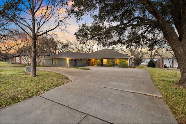 ranch-style home featuring a garage, driveway, and a yard