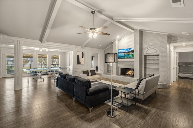 living room featuring a fireplace, dark wood-type flooring, ceiling fan, and lofted ceiling with beams