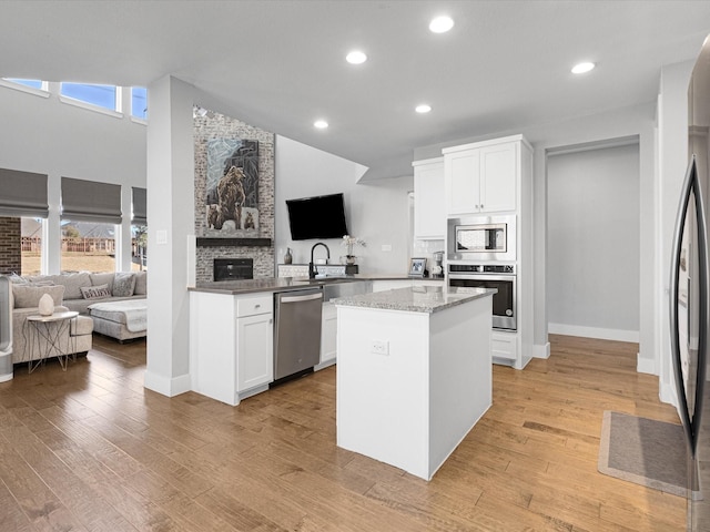 kitchen with appliances with stainless steel finishes, open floor plan, white cabinets, and a kitchen island