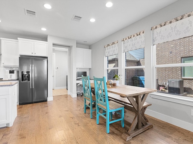 dining space with visible vents, light wood-style flooring, and baseboards