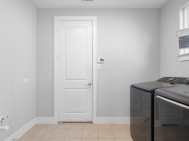 clothes washing area featuring light tile patterned floors, laundry area, independent washer and dryer, and baseboards