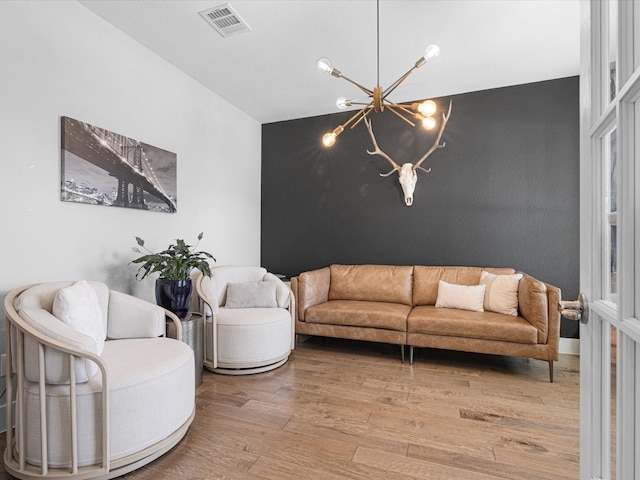 living area featuring light wood-style floors, visible vents, and a notable chandelier