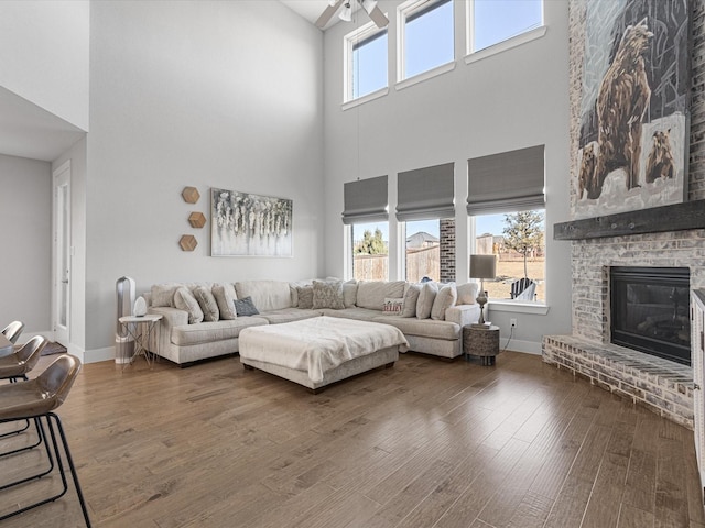 living area with baseboards, a healthy amount of sunlight, dark wood finished floors, and a fireplace