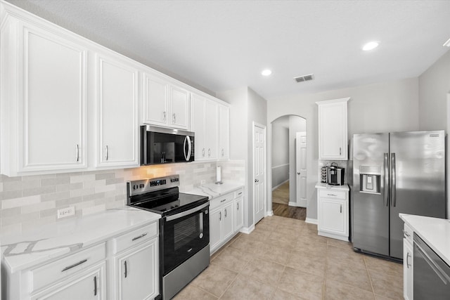 kitchen with open floor plan, stainless steel appliances, arched walkways, and white cabinets