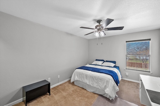 bedroom featuring light colored carpet, ceiling fan, a textured ceiling, and baseboards