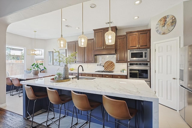 kitchen with stainless steel appliances, a breakfast bar area, an island with sink, and a sink