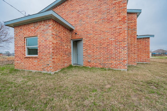 exterior space featuring brick siding and a yard