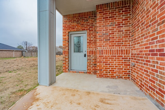 view of exterior entry with a patio area and brick siding