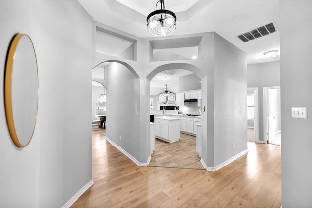 hallway featuring light wood-type flooring and a chandelier