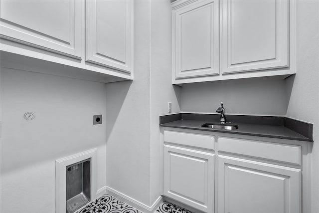 washroom with cabinet space, hookup for an electric dryer, a sink, and baseboards