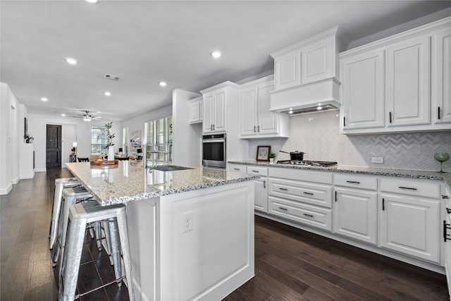 kitchen with stainless steel appliances, a kitchen island with sink, visible vents, and white cabinets