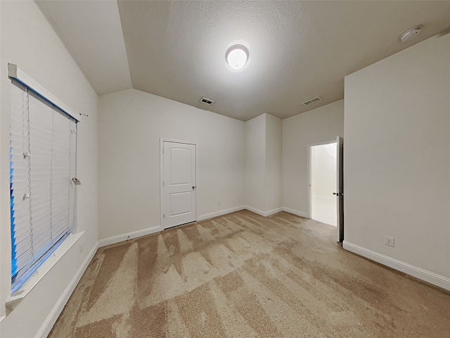 carpeted empty room featuring a textured ceiling and lofted ceiling