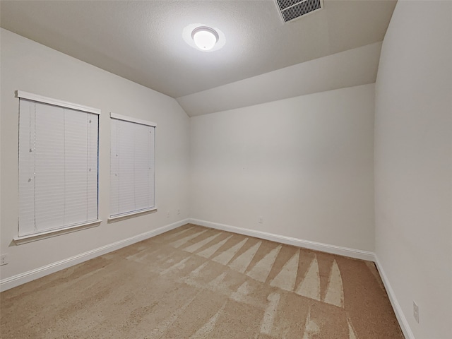 carpeted spare room with lofted ceiling