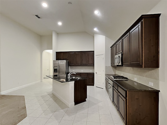 kitchen with a center island with sink, appliances with stainless steel finishes, backsplash, and light tile patterned flooring