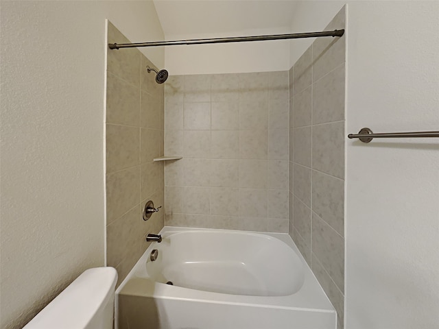 bathroom featuring toilet and tiled shower / bath combo