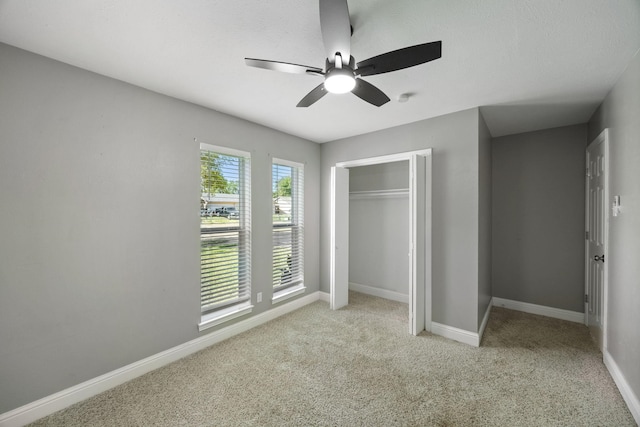 unfurnished bedroom featuring ceiling fan, a closet, and light colored carpet