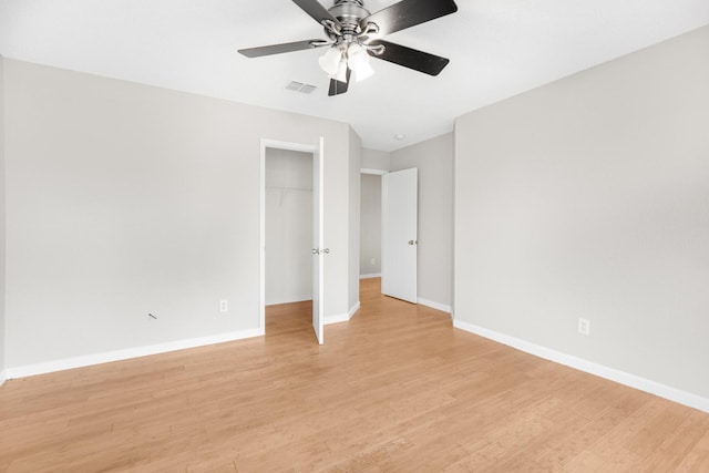 unfurnished bedroom with ceiling fan, light hardwood / wood-style flooring, a closet, and a spacious closet