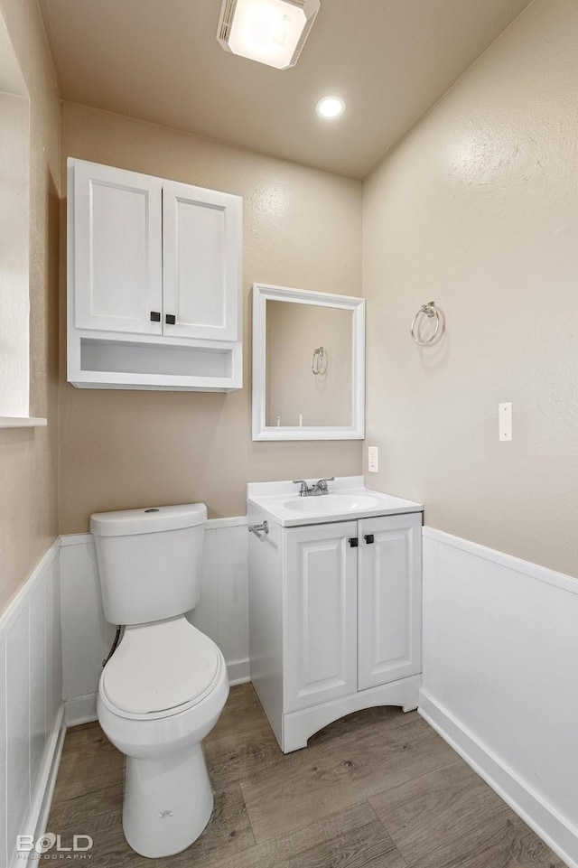 bathroom with hardwood / wood-style flooring, toilet, and vanity