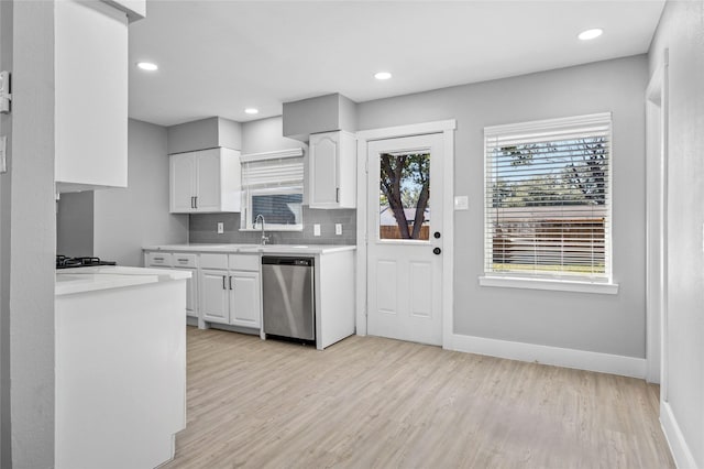 kitchen with light hardwood / wood-style floors, sink, dishwasher, white cabinets, and decorative backsplash