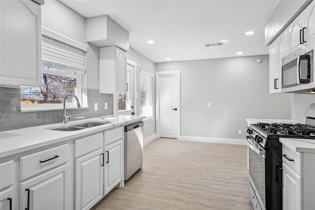 kitchen with appliances with stainless steel finishes, plenty of natural light, sink, and white cabinetry