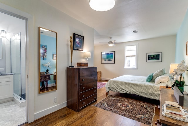 bedroom with connected bathroom, wood finished floors, visible vents, and baseboards