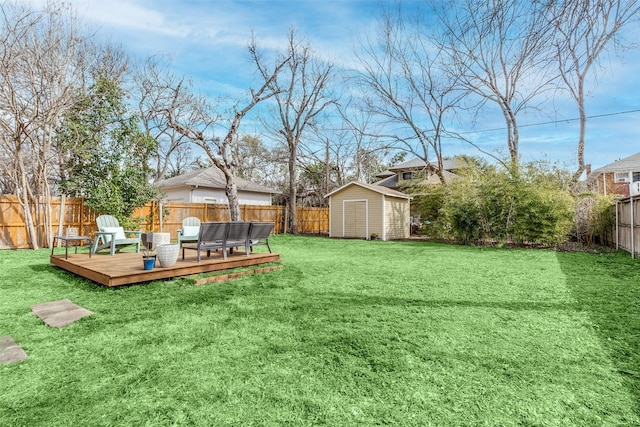 view of yard with an outbuilding, a storage unit, a fenced backyard, and a wooden deck