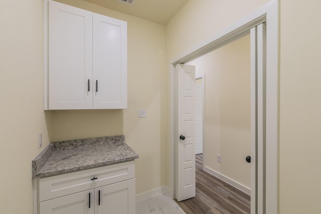 interior space with light stone countertops and white cabinets