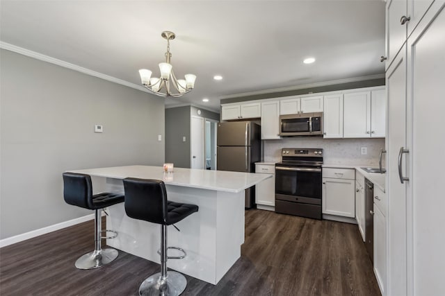 kitchen featuring hanging light fixtures, a center island, white cabinetry, and stainless steel appliances