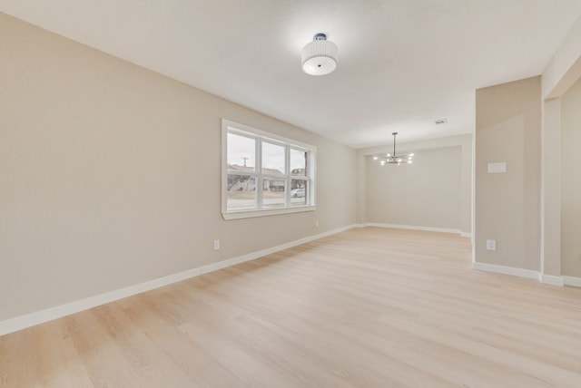 empty room with an inviting chandelier and light hardwood / wood-style floors