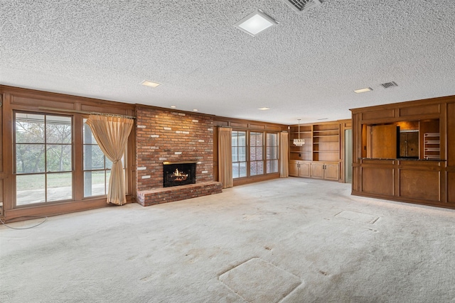 unfurnished living room with a fireplace, a textured ceiling, light colored carpet, and wood walls