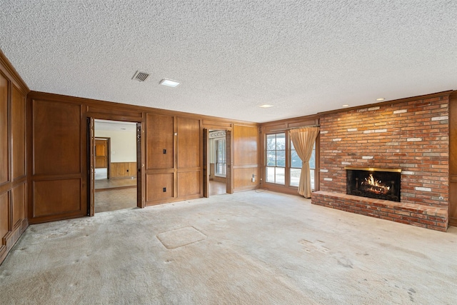 unfurnished living room featuring a brick fireplace, a textured ceiling, light colored carpet, and ornamental molding