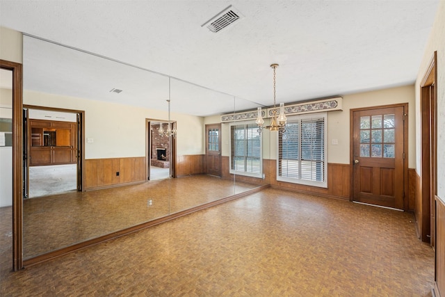 interior space featuring a textured ceiling, wooden walls, a notable chandelier, and parquet flooring