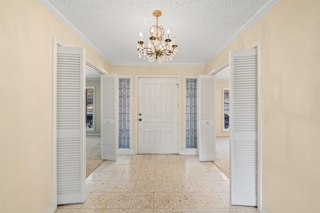 entryway featuring a notable chandelier, ornamental molding, and a textured ceiling