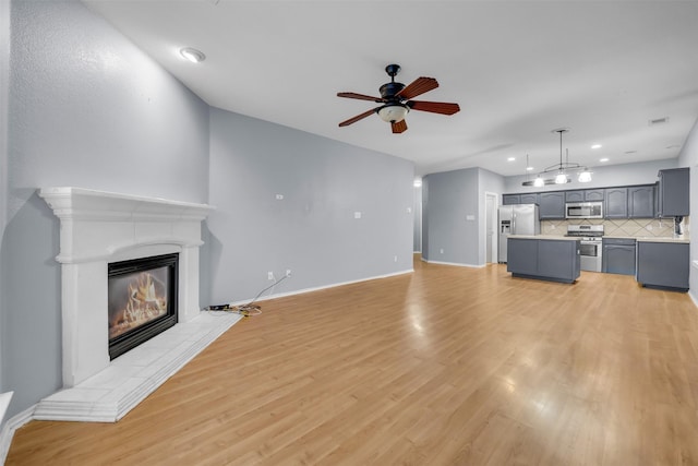 unfurnished living room with ceiling fan, light hardwood / wood-style flooring, and a tile fireplace