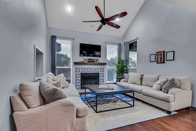 living room featuring a tile fireplace, high vaulted ceiling, hardwood / wood-style flooring, and ceiling fan