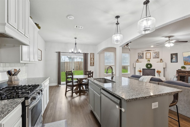 kitchen with sink, white cabinetry, pendant lighting, stainless steel appliances, and a kitchen island with sink