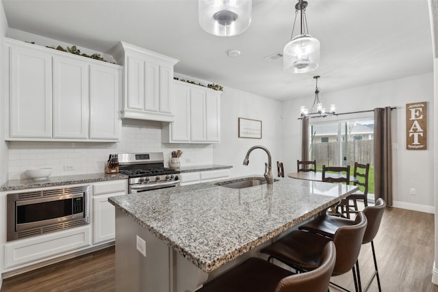kitchen with white cabinetry, stainless steel appliances, a kitchen island with sink, and sink