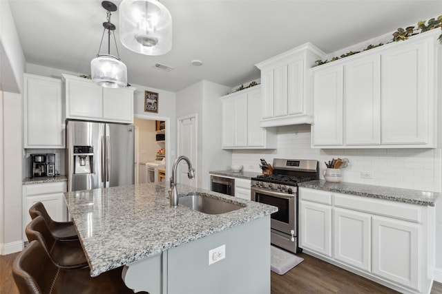 kitchen with a center island with sink, appliances with stainless steel finishes, washer and clothes dryer, and white cabinets