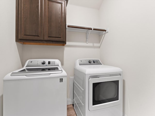 washroom with cabinet space, washing machine and clothes dryer, and wood finished floors